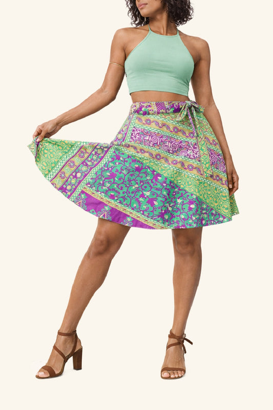 Woman wearing a green and purple patterned skirt with a light green top on a white background