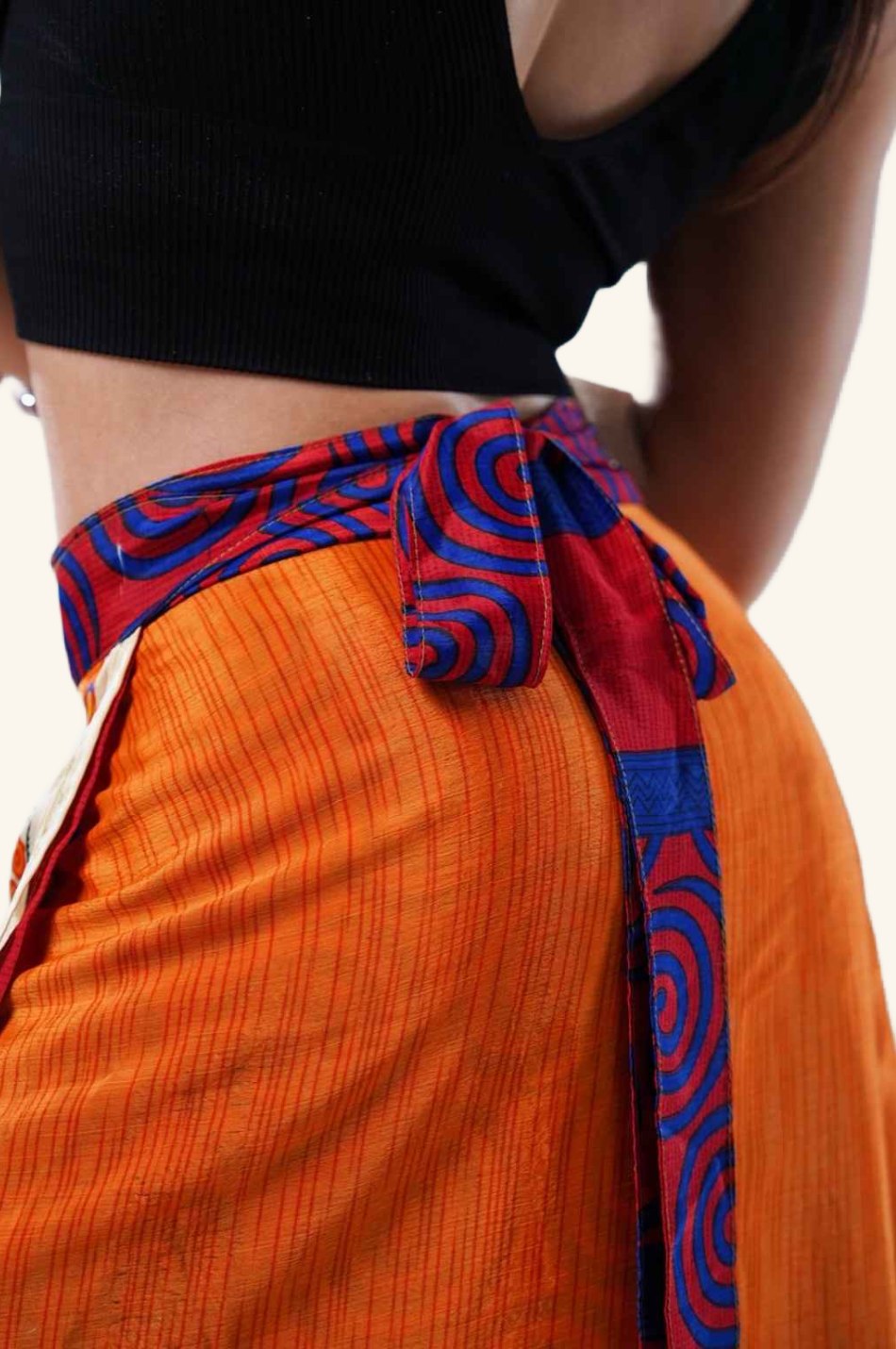 Model showing back view of short wrap skirt with orange floral design