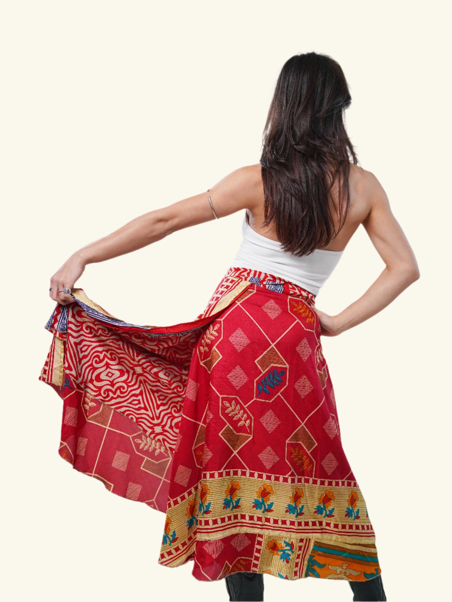 Model in FREEYA wrap skirt made from vintage saris, red print with floral border, turning pose in studio