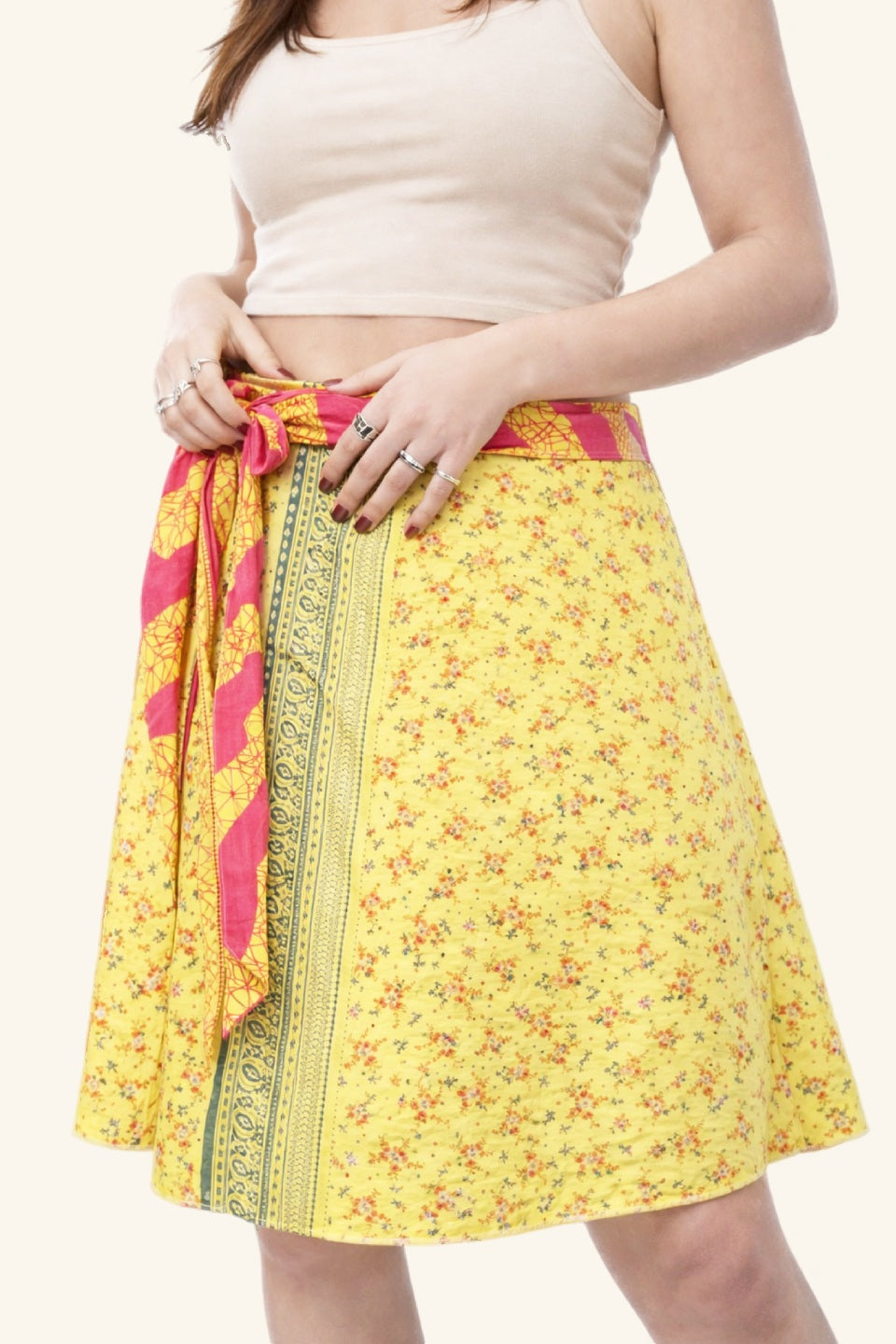Yellow floral skirt with pink and green accents worn by a person on a white background