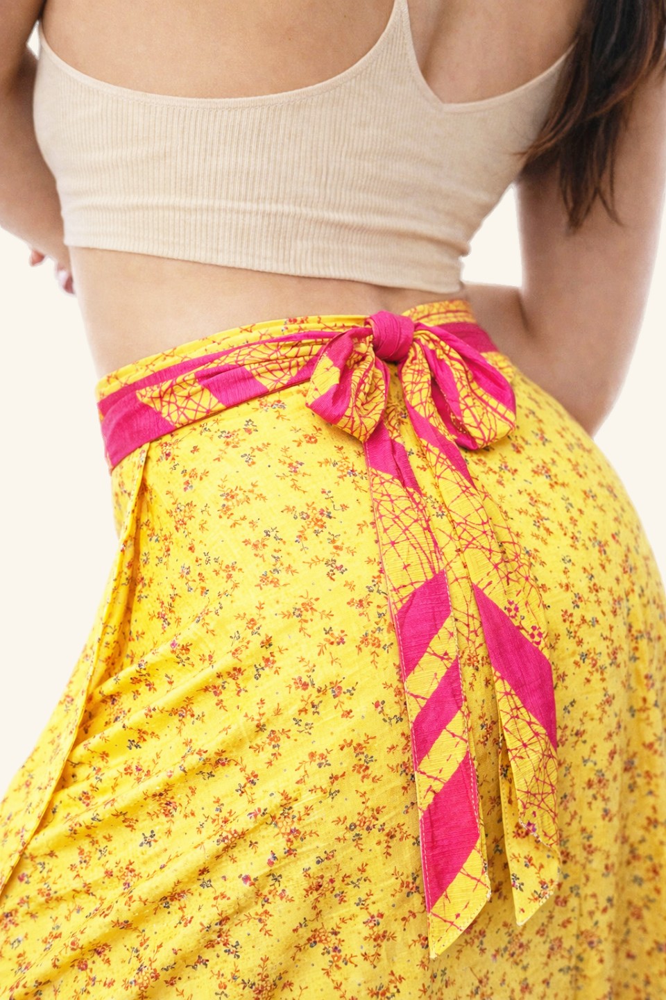 Yellow floral skirt with pink tie detail worn by a person