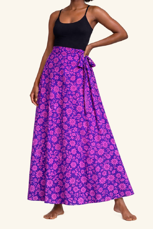 Woman wearing a black top and purple floral skirt on a white background