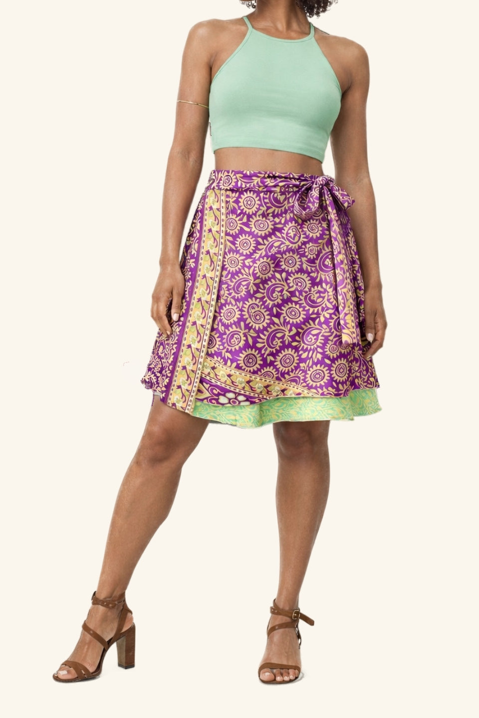Woman wearing a green crop top and purple patterned skirt on a white background