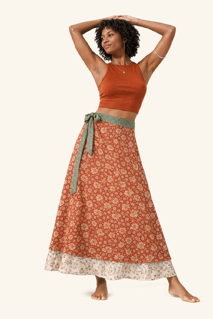 Woman wearing a rust-colored top and floral skirt on a white background